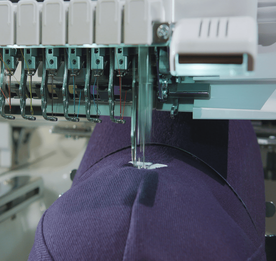 Close-up of an embroidery machine stitching a pattern on purple fabric.