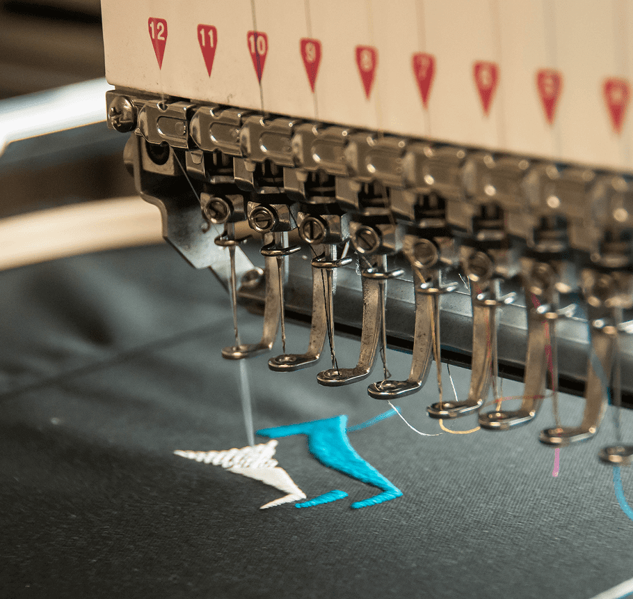 Close-up of an embroidery machine stitching a blue and white design.