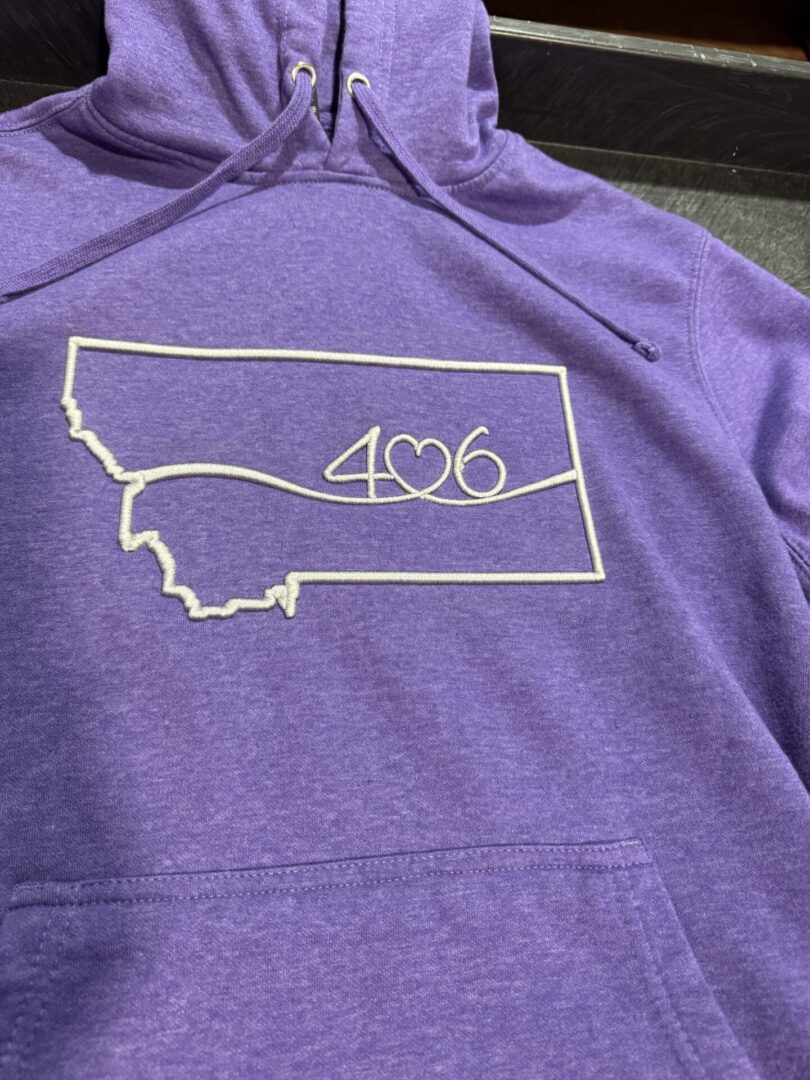 Purple hoodie with Montana state outline and 406 embroidered.